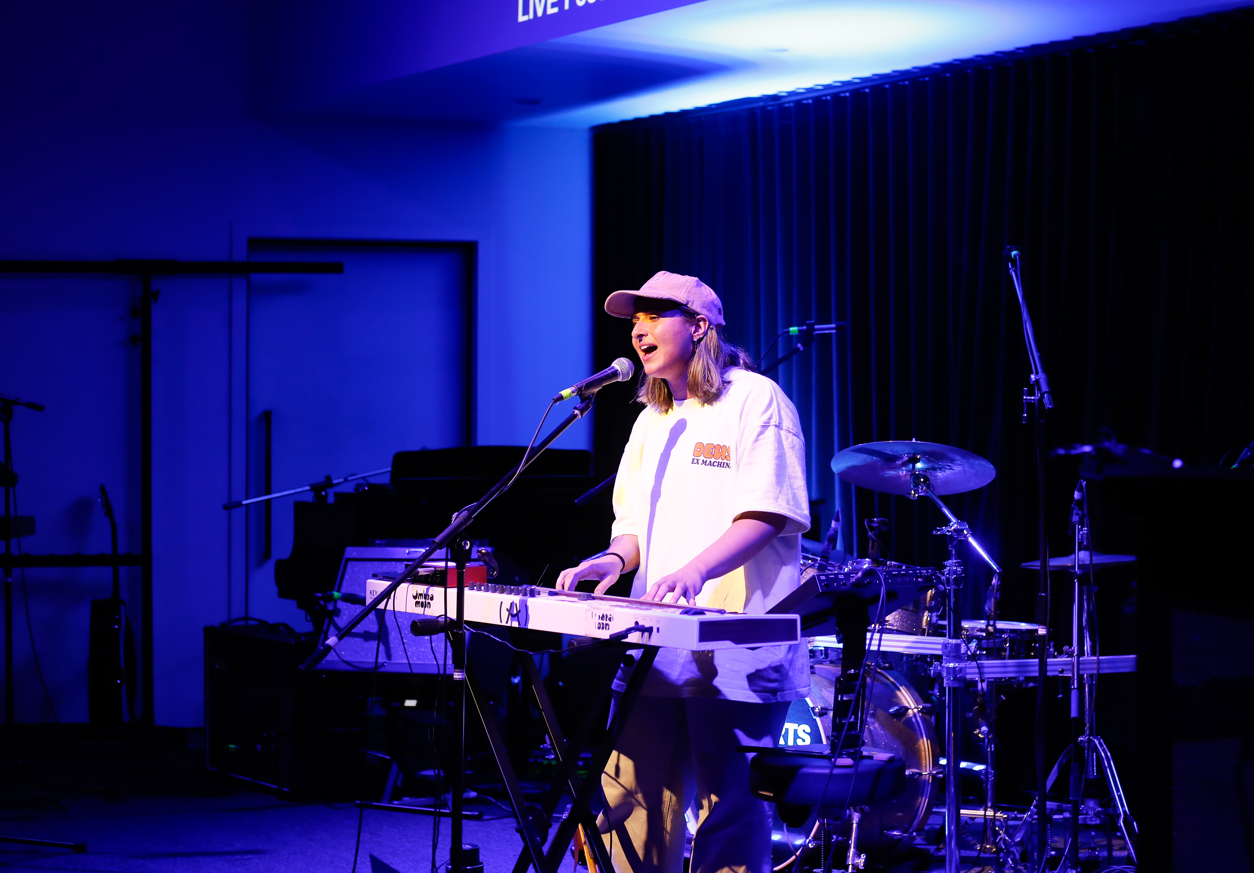 Collarts music production student performing on stage, singing and playing on the keyboard