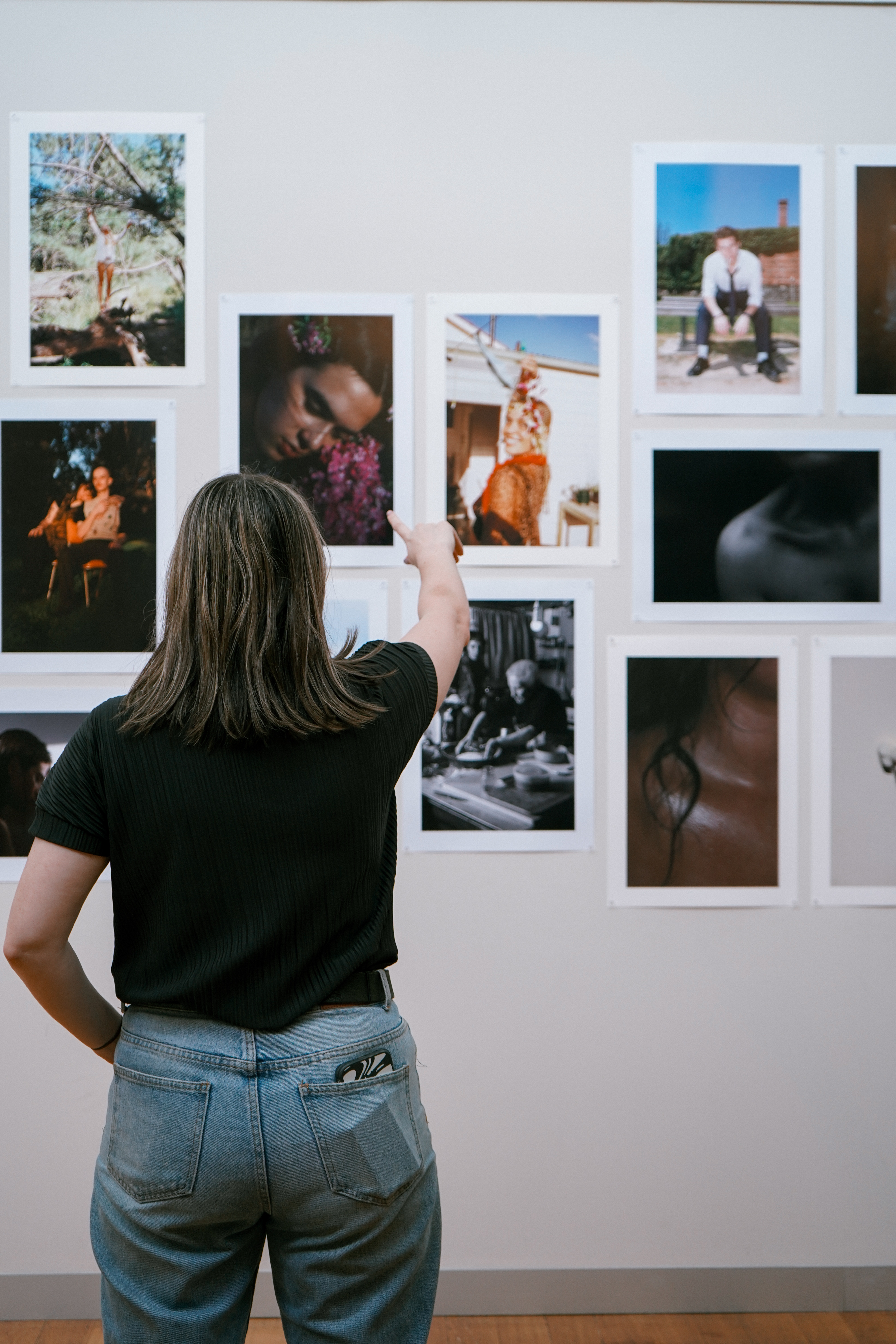 Collarts photography student pointing at a wall of photos 