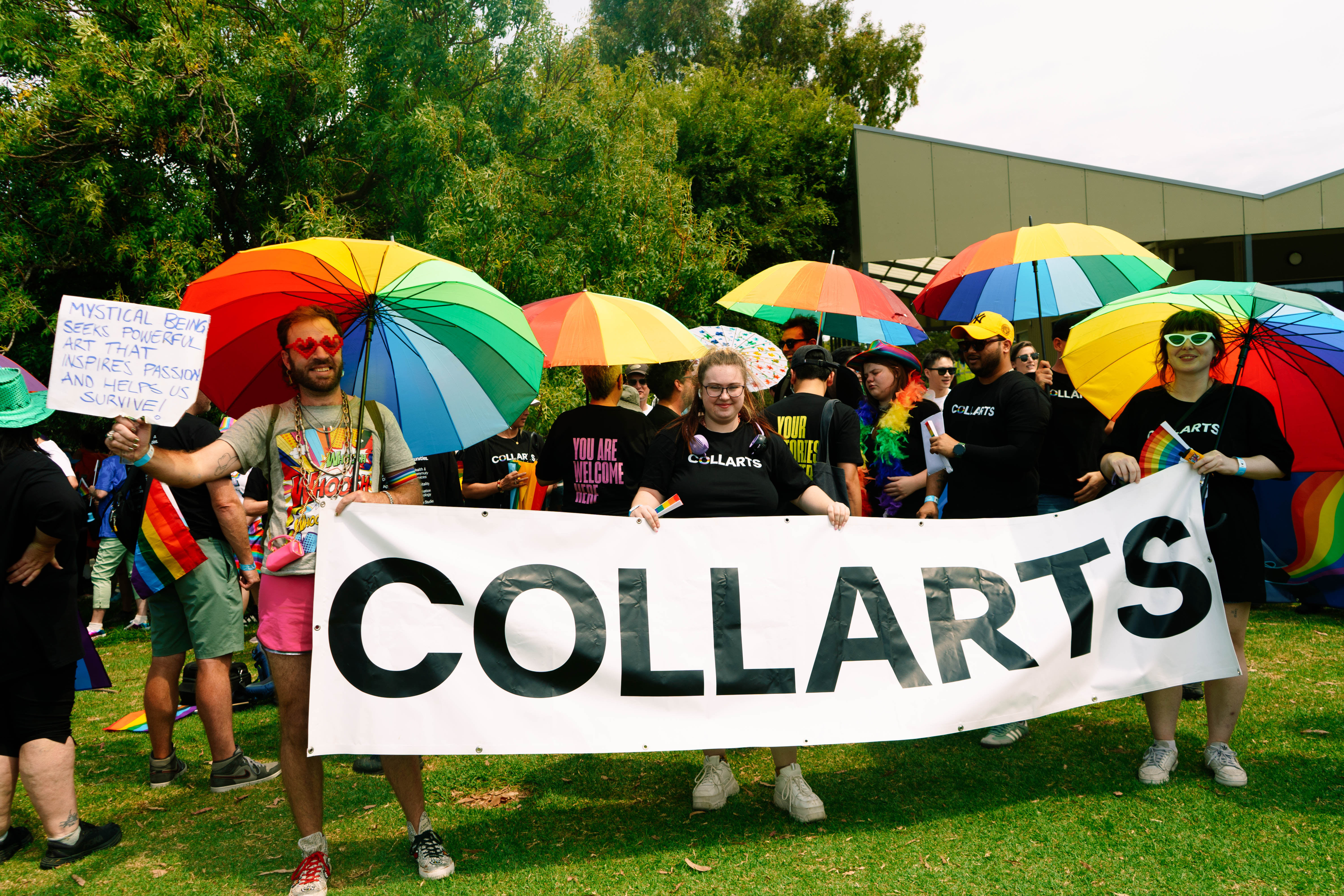 Group of Collarts students holding rainbow umbrellas and a large Collarts banner at 2025 Midsumma festival