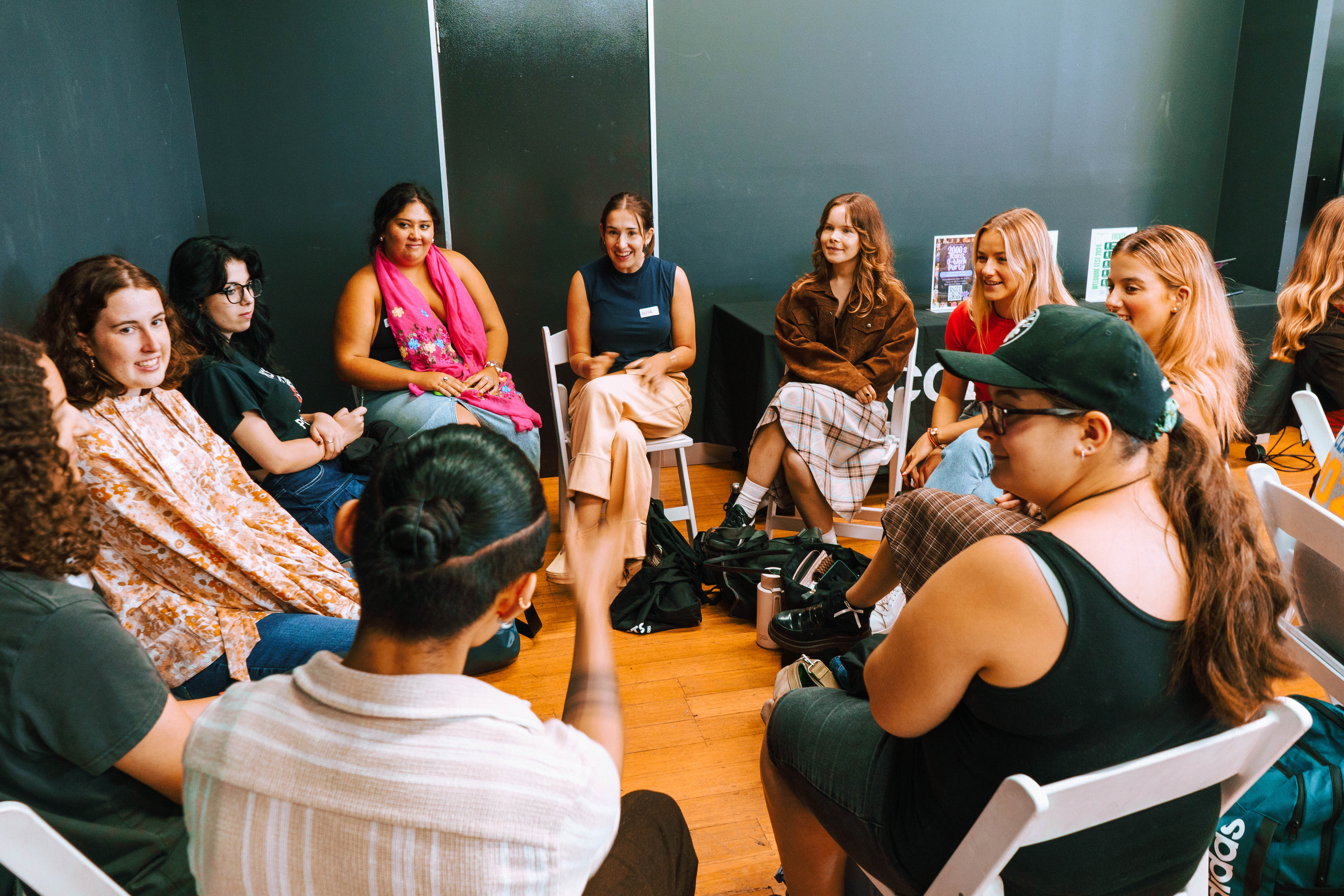 Group of Collarts students sitting on chairs in a circle, smiling and chatting