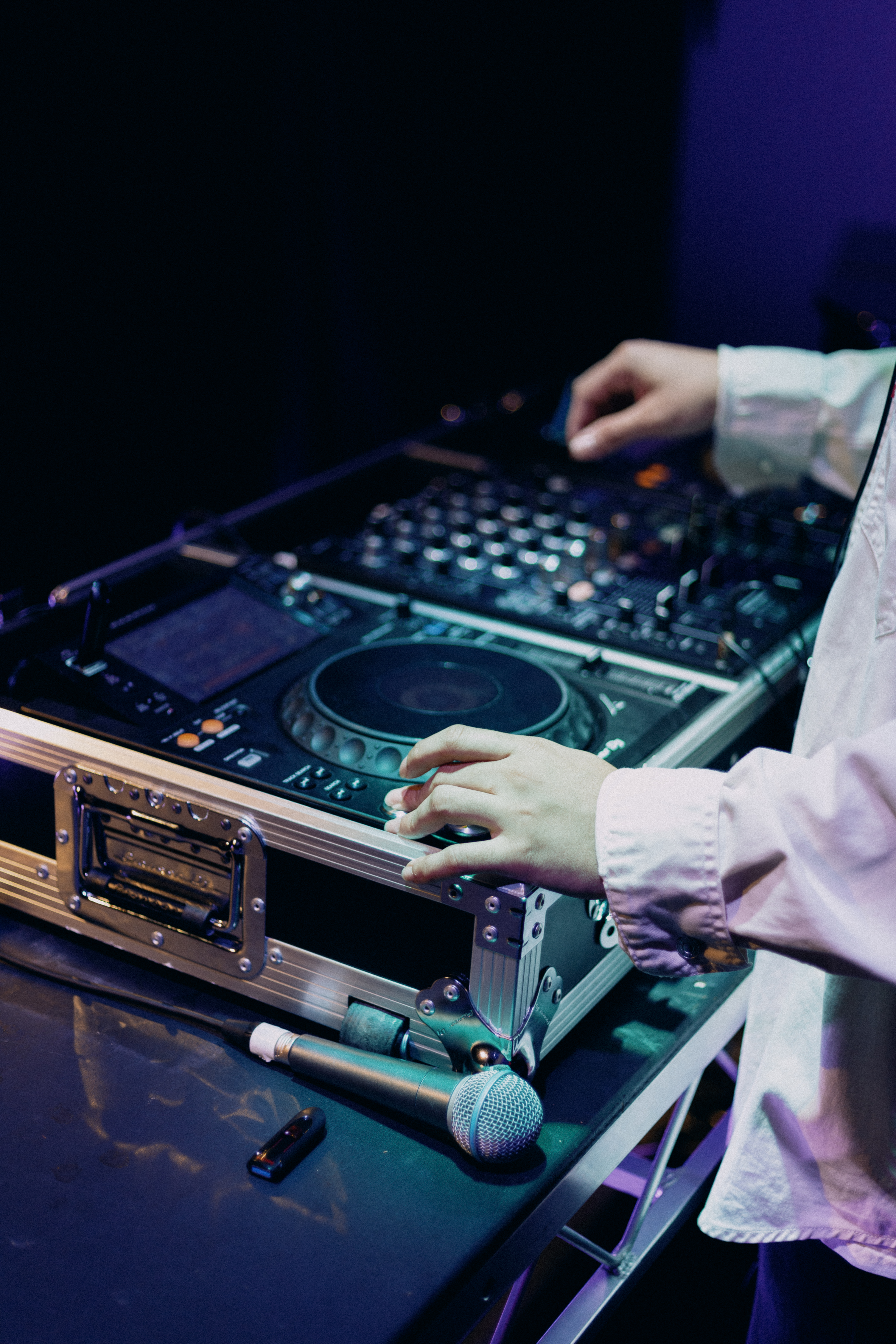 close up of dj deck and microphone with collarts students' hands on the deck
