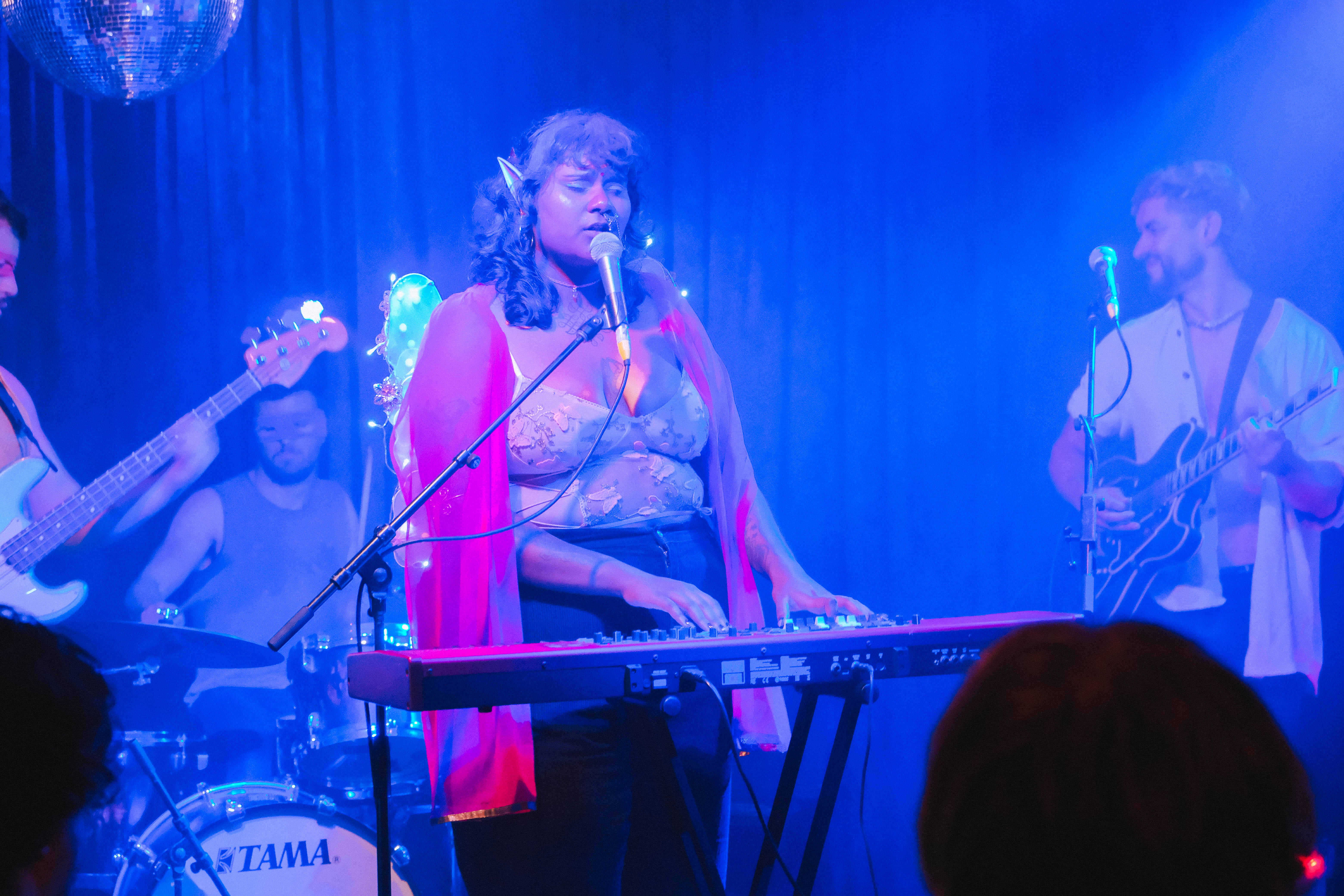 Collarts music production performing on stage, singing into a microphone while playing the keyboard